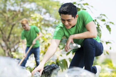 Young handsome man picking up litter in the forest